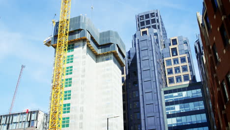 LONDON---MAY,-2017:-Crane-and-modern-buildings-under-construction-against-blue-sky-in-the-City-of-London