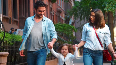 Couple-swinging-their-daughter-as-they-walk-down-the-street
