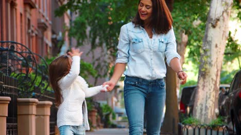Young-mother-and-daughter-walking-in-the-street,-front-view