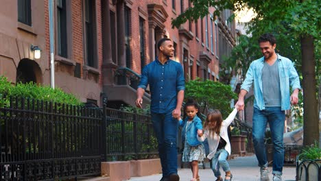 Two-fathers-and-their-daughters-walk-in-the-street-talking