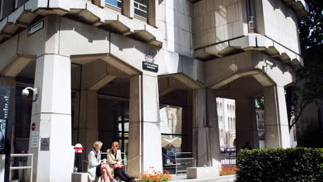 LONDON---MAY,-2017:-Two-women-sit-talking-under-arches-at-the-entrance-to-Guildhall,-London,-EC2