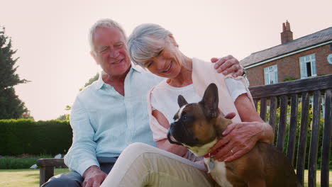 Älteres-Paar-Sitzt-Auf-Gartenbank-Mit-Französischer-Bulldogge