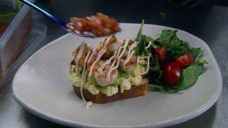 El-Chef-Pone-Mermelada-De-Tomate-Sobre-Una-Tostada-Con-Huevos-Revueltos,-Aguacate-Y-Camarones-Fritos