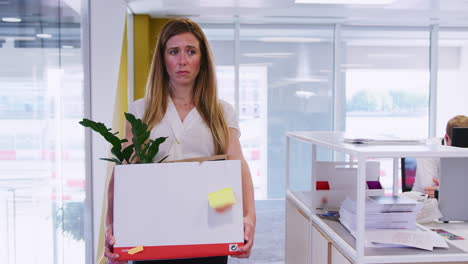 Young-woman-holding-box-of-her-belongings-leaving-an-office
