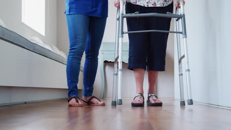 Nurse-helping-senior-woman-use-a-walking-frame,-low-section