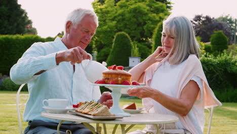 Retired-Couple-Enjoying-Afternoon-Tea-In-Garden-At-Home