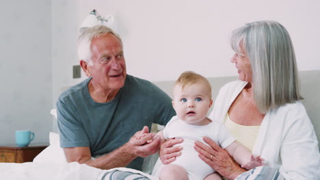 Grandparents-Lying-In-Bed-At-Home-Looking-After-Baby-Grandson