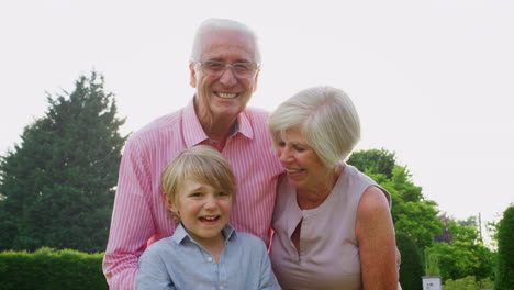 Grandparents-and-grandson-smiling-to-camera-in-the-garden