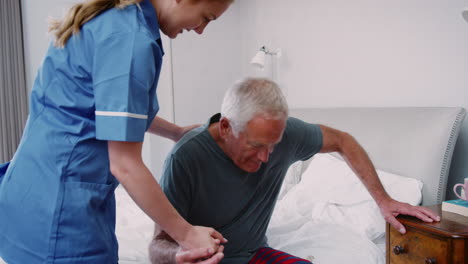 Krankenschwester-Hilft-älterem-Mann-Bei-Hausbesuch-Aus-Dem-Bett