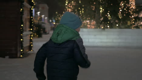 Kind-Läuft-In-Verschneiter-Straße-Mit-Weihnachtsbeleuchtung
