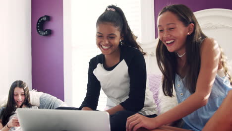 Dos-Chicas-Adolescentes-Sentadas-En-La-Cama-Usando-Una-Computadora-Portátil,-De-Cerca