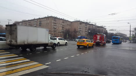 Calle-De-Moscú-Con-Tráfico-De-Automóviles-En-Carreteras-Mojadas-Y-Bomberos-Pasando-Por-Rusia