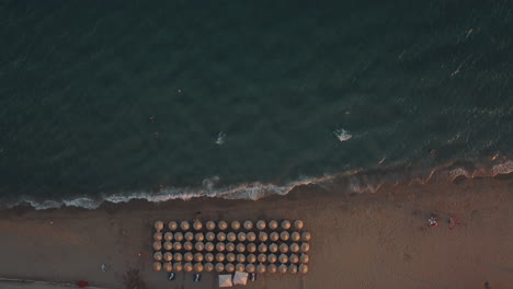 Toma-Aérea-Del-Mar-Azul-Y-Tumbonas-Bajo-Sombrillas-En-La-Playa