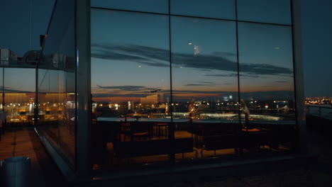 Stadt-Bei-Nacht-Und-Startendes-Flugzeug-Im-Spiegelbild-Des-Fensters