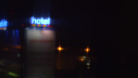 Window-view-to-night-street-with-illuminated-hotel-banner