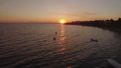 Luftaufnahme-Des-Sonnenuntergangs-Am-Meer-Mit-Booten-Und-Resort-An-Der-Küste-Griechenlands