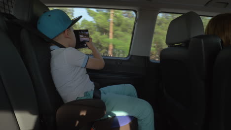 Boy-taking-pictures-with-cell-when-traveling-by-car