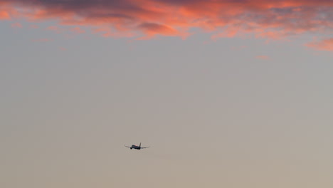 Airplane-flying-in-evening-sky-with-red-clouds