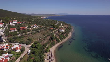 Volando-Sobre-Cabañas-De-Mar-Y-Resort-En-La-Costa-De-La-Playa-De-Trikorfo,-Grecia