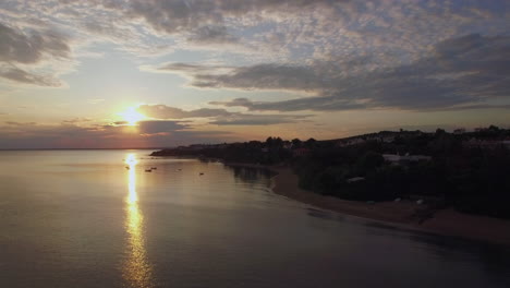 Küste-Mit-Häusern-Und-Goldenem-Sonnenuntergang-über-Dem-Meer.-Luftaufnahmen-Vom-Strand-Von-Trikorfo,-Griechenland
