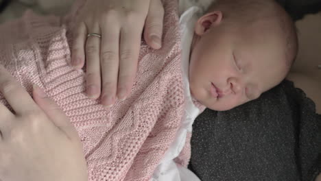Mother-stroking-beloved-newborn-daughter-sleeping-on-her-chest