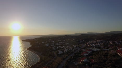 Luftaufnahme-Des-Sonnenuntergangs-Von-Meer-Und-Küste-Mit-Häusern-Am-Strand-Von-Trikorfo,-Griechenland