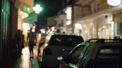 Calle-De-La-Ciudad-Nocturna-Con-Autos-Estacionados-Y-Pancartas-Iluminadas.