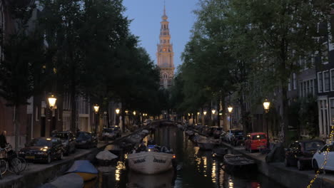 Vista-De-La-Iglesia-Del-Sur-Zuiderkerk-Y-El-Canal-Con-Barcos-En-Primer-Plano-Ámsterdam,-Países-Bajos