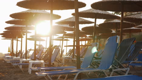 Chaise-Longues-Vacías-En-El-Resort-Y-Gente-Saliendo-De-La-Playa-Al-Atardecer