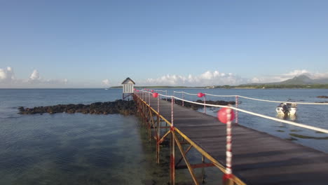 Aerial-view-of-coast-line-of-Mauritius-Island-water-laves-camera-moves-along-pear-in-sea-against-sky