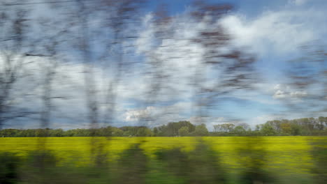 View-from-riding-train-window-of-coutryside-landscape-against-cloudy-sky