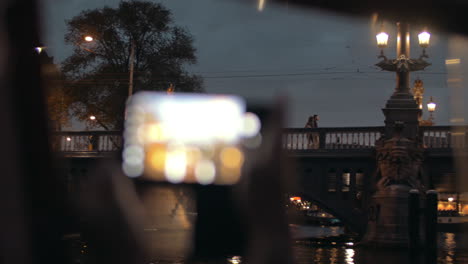 Abendansicht-Der-Nahaufnahme-Einer-Frauenhand-Mit-Smartphone,-Die-Ein-Foto-Von-Blauwbrug-Amsterdam-Niederlande-Macht