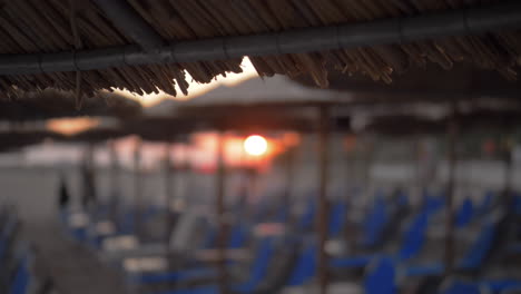 Beach-with-chaise-longues-and-straw-umbrellas-at-sunset