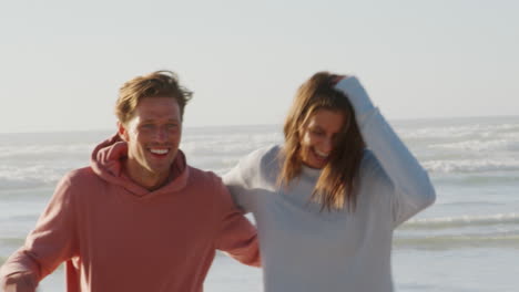 Couple-Having-Fun-Running-Along-Winter-Beach-Together