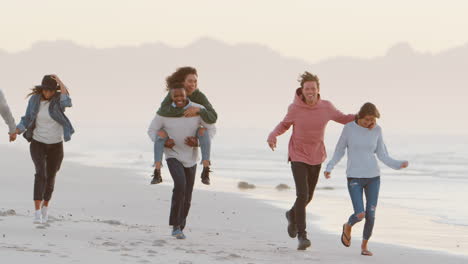 Group-Of-Friends-Having-Fun-Running-Along-Winter-Beach-Together