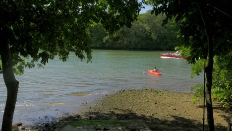 Blick-Auf-Den-Fluss-Mit-Mann-Im-Kanu-Und-Motorbooten