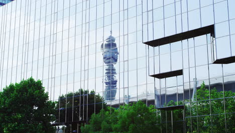 LONDON---MAY,-2017:-BT-Tower-and-treetops-reflected-in-modern-glass-fronted-buildings-against-blue-sky,-London,-W1