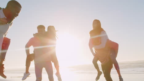 Group-Of-Friends-Having-Piggyback-Race-On-Winter-Beach-Together