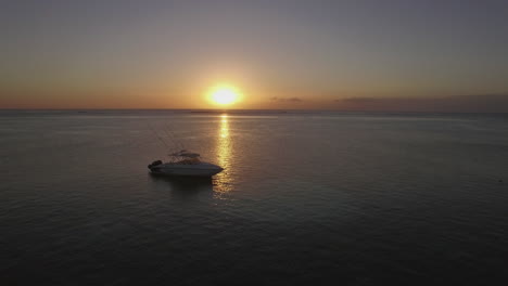 Flying-over-the-yacht-in-ocean-at-sunset