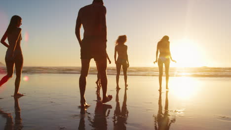 Friends-Walking-Towards-Waves-At-Sunset-On-Beach-Vacation