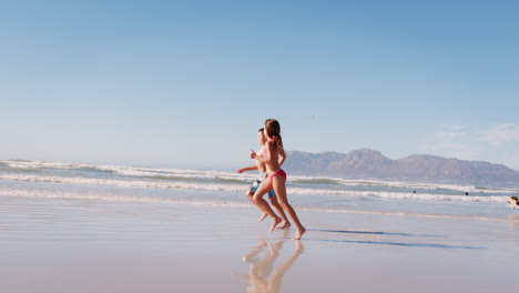 Junge-Und-Mädchen-Laufen-Im-Sommerurlaub-Gemeinsam-Am-Strand-Entlang