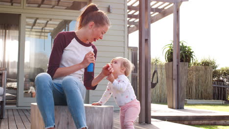 Young-white-mother-and-daughter-blowing-bubbles-outdoors