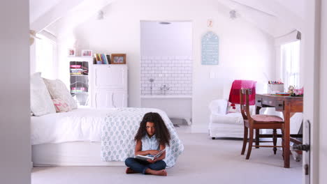 Young-black-girl-reading-a-book-alone-in-her-bedroom