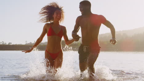 Young-mixed-race-couple-running-and-splashing-in-a-lake