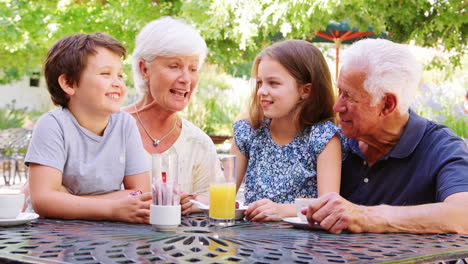 Kids-sitting-outdoors-in-a-park-cafe-with-their-grandparents