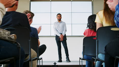 High-School-Students-Applaud-Male-Teacher-Giving-Presentation-In-Front-Of-Screen