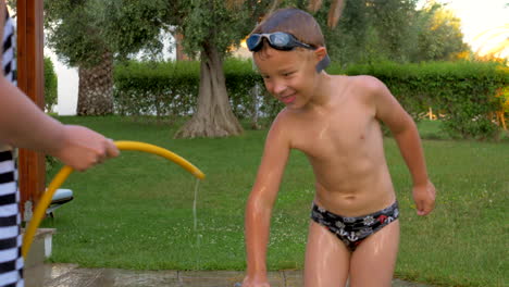 Mum-and-son-having-fun-with-pouring-over-from-hose