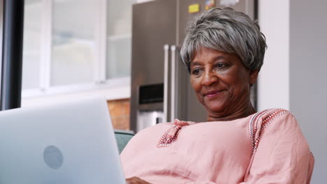 Ältere-Frau-Entspannt-Sich-Zu-Hause-Auf-Dem-Sofa-Und-Nutzt-Ihren-Laptop,-Um-Online-Einzukaufen