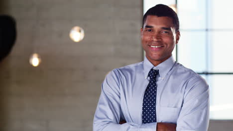 Young-mixed-race-businessman-smiling-to-camera-in-an-office