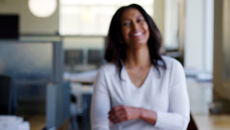 Mixed-raced-businesswoman-walking-into-focus-in-office